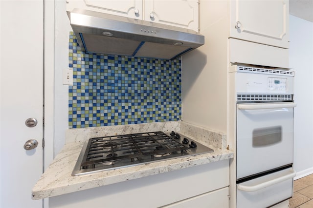 kitchen with stainless steel gas cooktop, oven, and white cabinetry