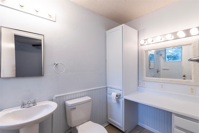 bathroom with tile patterned flooring, toilet, sink, and a textured ceiling