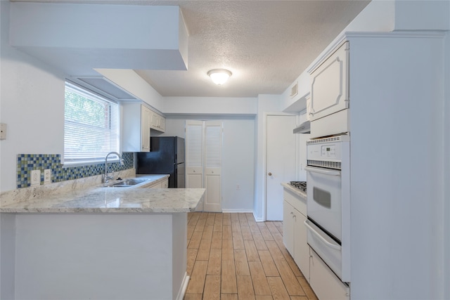 kitchen featuring white cabinetry, backsplash, kitchen peninsula, sink, and light hardwood / wood-style floors