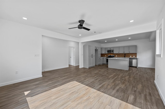 unfurnished living room featuring ceiling fan, sink, and dark hardwood / wood-style flooring