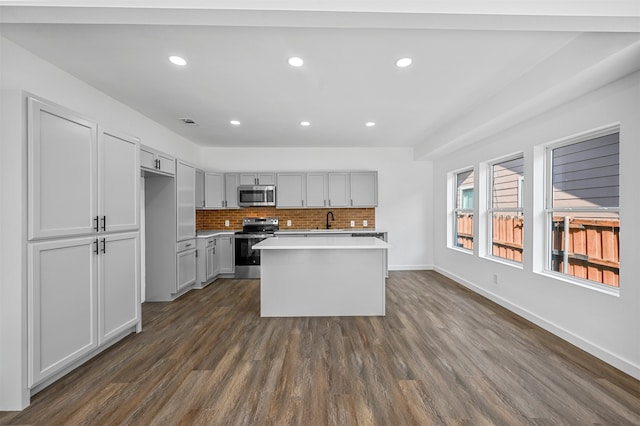 kitchen with gray cabinetry, stainless steel appliances, dark hardwood / wood-style flooring, sink, and a kitchen island with sink