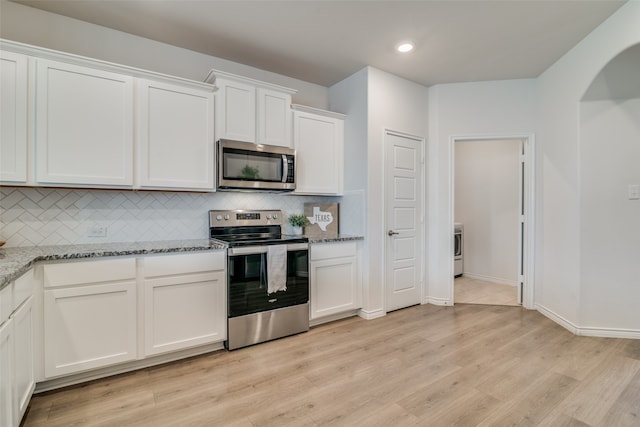 kitchen featuring white cabinets, appliances with stainless steel finishes, stone countertops, and light hardwood / wood-style flooring