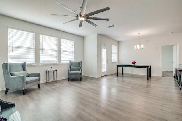 living area with light wood-type flooring, ceiling fan with notable chandelier, and a wealth of natural light