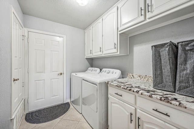 washroom with a textured ceiling, cabinets, washer and dryer, and light tile patterned flooring