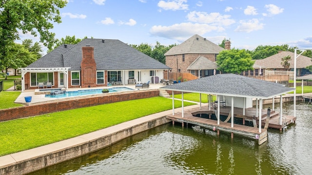 view of dock with a water view, a lawn, and a patio area