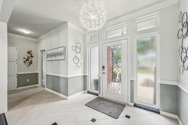 foyer entrance featuring a textured ceiling, crown molding, a chandelier, and light tile patterned flooring