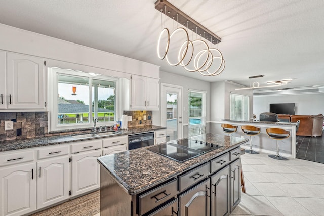 kitchen featuring black appliances, sink, hanging light fixtures, and white cabinetry