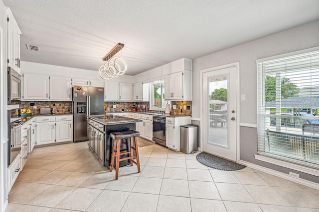 kitchen with a kitchen island, black appliances, backsplash, sink, and white cabinetry