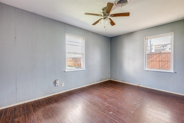 empty room with a ceiling fan, hardwood / wood-style flooring, visible vents, and a healthy amount of sunlight