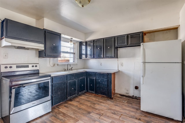 kitchen featuring electric stove, dark wood-style flooring, freestanding refrigerator, a sink, and under cabinet range hood