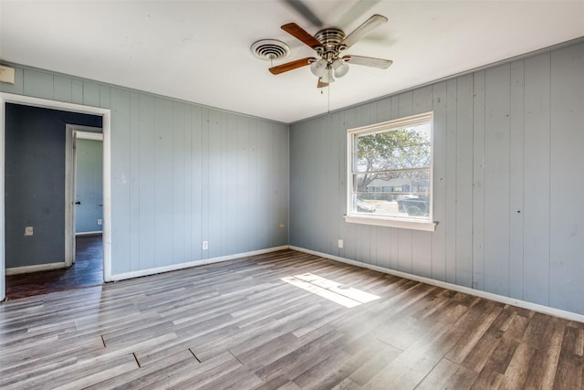 unfurnished room featuring visible vents, ceiling fan, baseboards, and wood finished floors