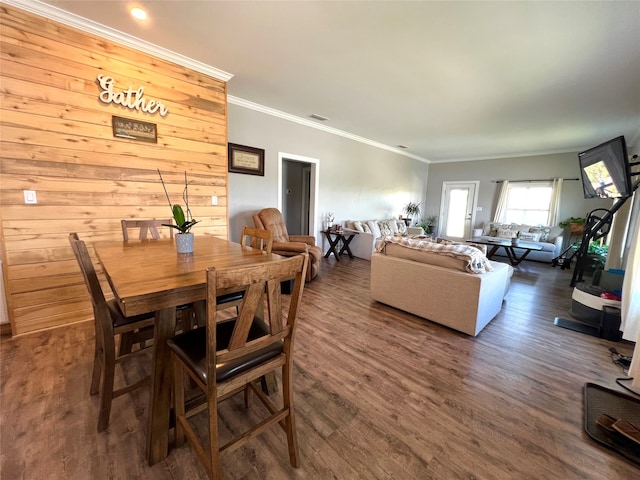 dining space with ornamental molding, dark wood-type flooring, and wooden walls