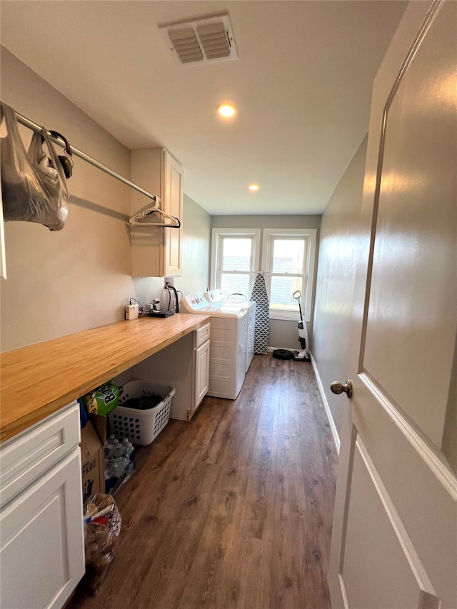 laundry area featuring washing machine and clothes dryer, cabinets, and dark hardwood / wood-style floors