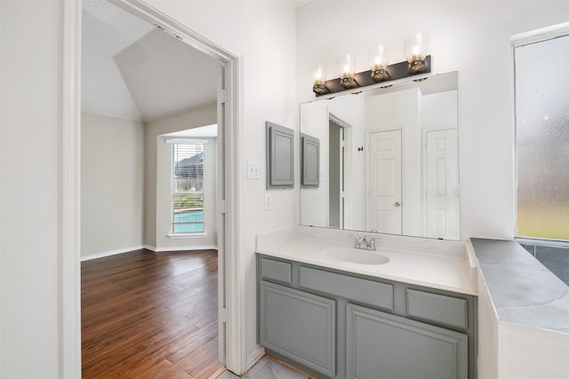 bathroom featuring lofted ceiling, vanity, hardwood / wood-style floors, and a textured ceiling