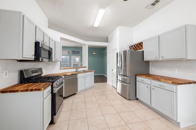 kitchen featuring sink, appliances with stainless steel finishes, butcher block countertops, and white cabinets