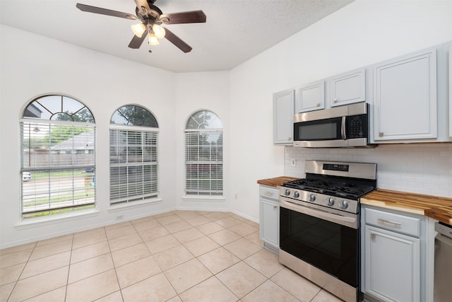 kitchen with tasteful backsplash, a textured ceiling, butcher block countertops, stainless steel appliances, and ceiling fan