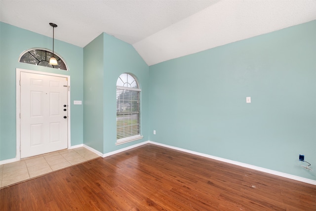 entrance foyer with lofted ceiling, hardwood / wood-style floors, and a textured ceiling