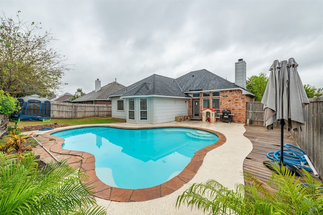 view of pool with a wooden deck, a trampoline, and french doors