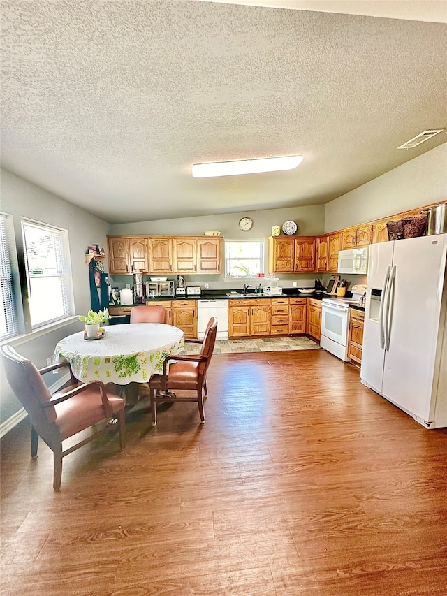 kitchen with a wealth of natural light, light wood-type flooring, white appliances, and a textured ceiling