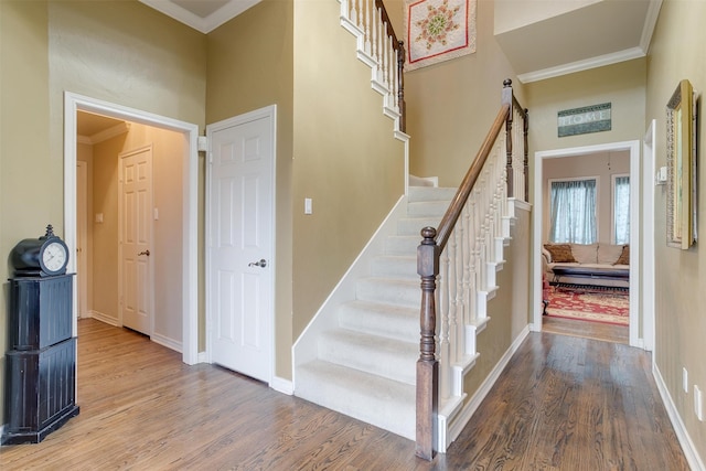 stairway featuring ornamental molding, hardwood / wood-style floors, and a high ceiling