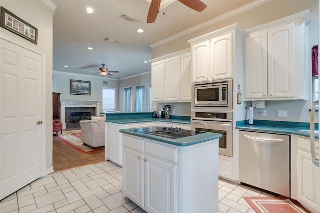 kitchen featuring a fireplace, crown molding, appliances with stainless steel finishes, white cabinets, and ceiling fan