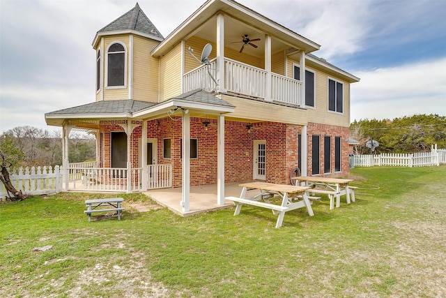 back of property with a lawn, a balcony, a patio, and ceiling fan