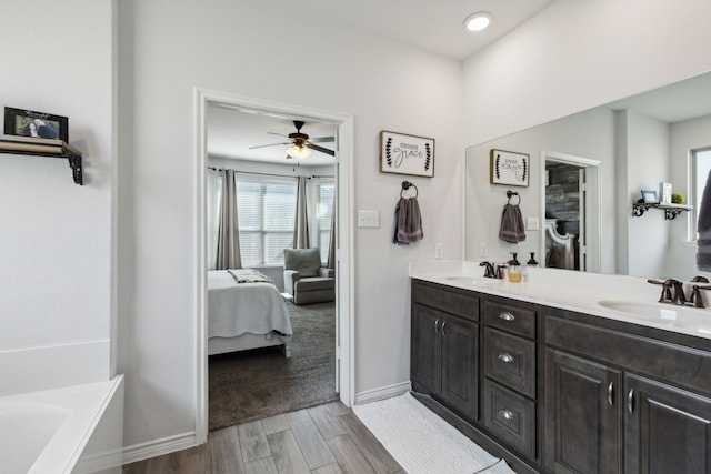 bathroom featuring vanity, hardwood / wood-style flooring, ceiling fan, and a washtub