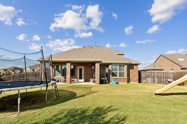 back of property featuring a trampoline, a playground, a lawn, and a patio area