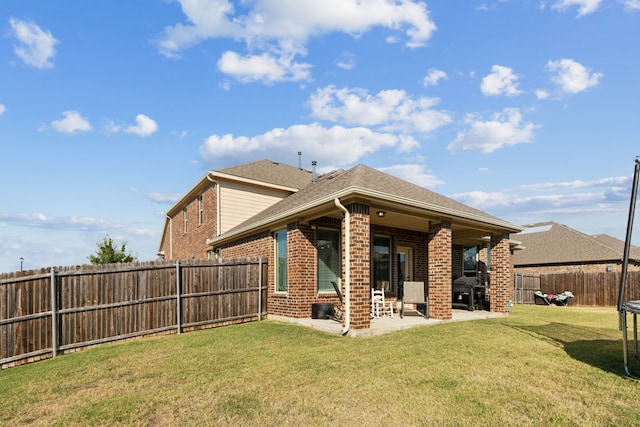 rear view of property featuring a yard and a patio area