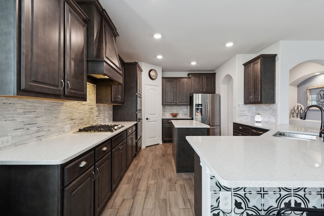 kitchen with stainless steel appliances, kitchen peninsula, sink, a breakfast bar area, and light hardwood / wood-style floors