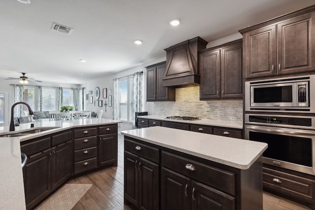 kitchen featuring light hardwood / wood-style flooring, stainless steel appliances, premium range hood, sink, and ceiling fan