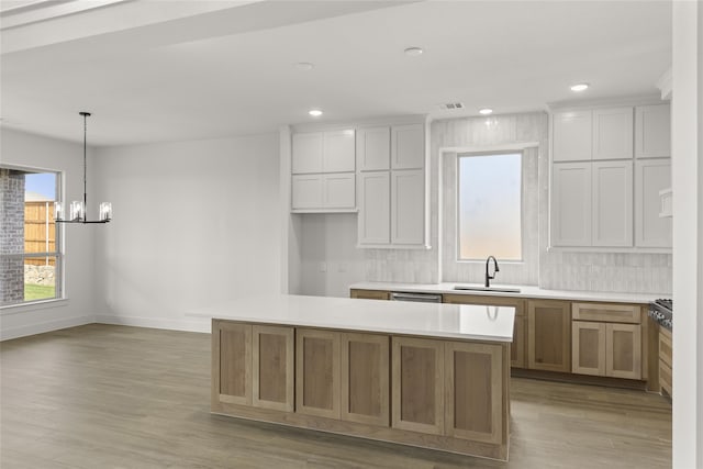 kitchen with white cabinets, sink, light wood-type flooring, and a kitchen island