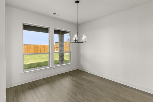 unfurnished dining area with dark wood-type flooring and a chandelier