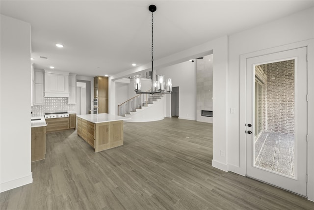 kitchen featuring dark hardwood / wood-style flooring, a center island, hanging light fixtures, tasteful backsplash, and white cabinetry