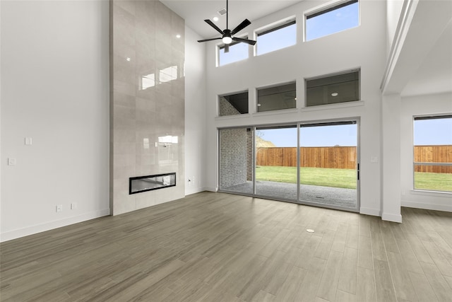 unfurnished living room featuring a fireplace, a healthy amount of sunlight, and a towering ceiling