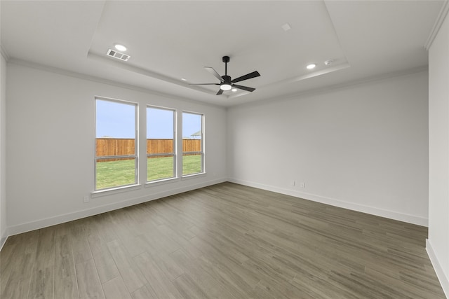 unfurnished room featuring hardwood / wood-style floors, ceiling fan, a raised ceiling, and crown molding