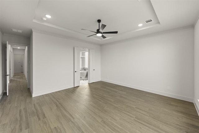 empty room with hardwood / wood-style flooring, ceiling fan, a tray ceiling, and ornamental molding