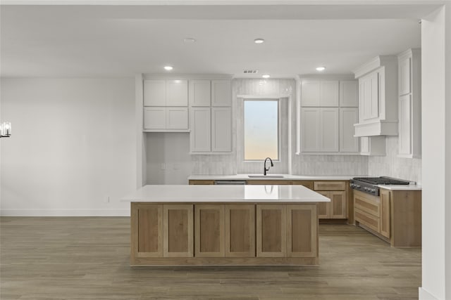 kitchen with white cabinets, light hardwood / wood-style flooring, sink, and a center island