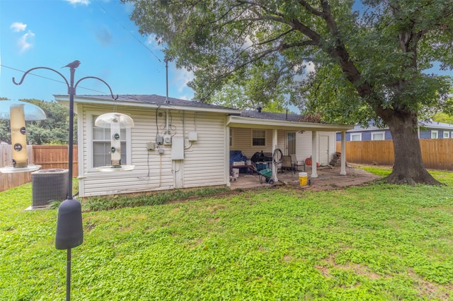 rear view of house with central AC unit, a patio area, and a yard