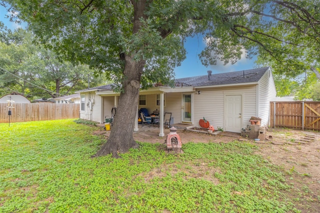 back of house with a lawn and a patio