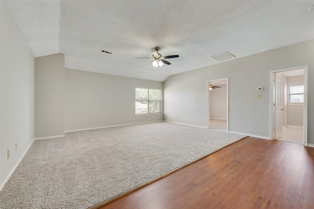 spare room with lofted ceiling, hardwood / wood-style floors, ceiling fan, and a textured ceiling