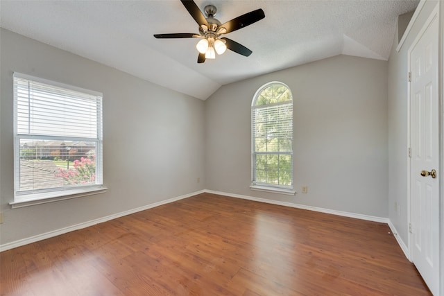 empty room featuring lofted ceiling, wood-type flooring, ceiling fan, and a textured ceiling