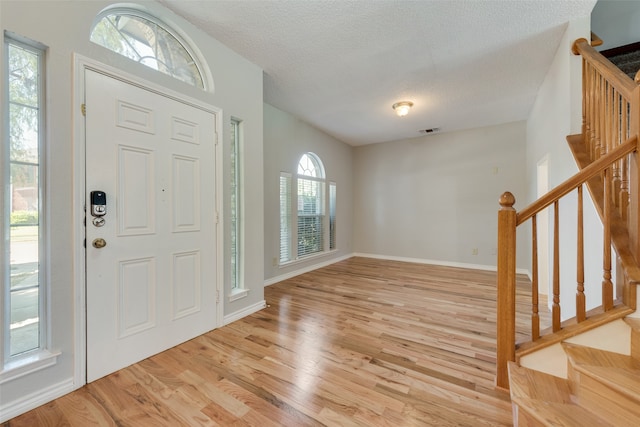 foyer entrance with a textured ceiling, a healthy amount of sunlight, and light wood-type flooring