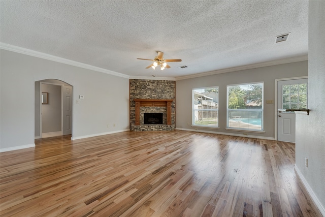 unfurnished living room with a textured ceiling, a fireplace, ornamental molding, ceiling fan, and light wood-type flooring