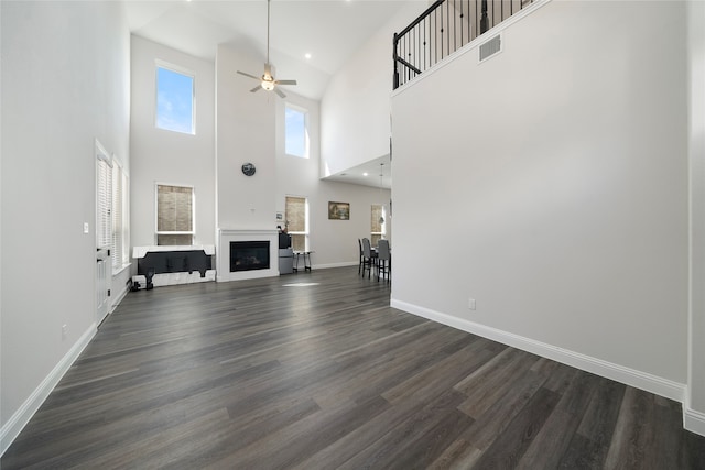 unfurnished living room with a high ceiling, ceiling fan, and dark wood-type flooring