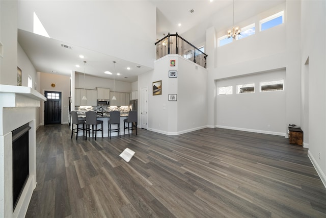 living room featuring a chandelier, a high ceiling, and dark hardwood / wood-style flooring