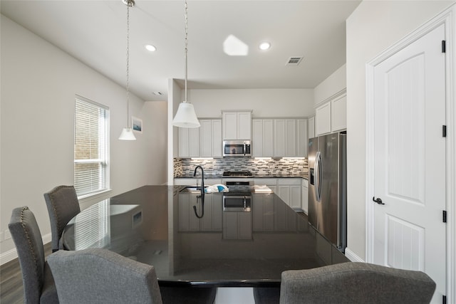 kitchen with appliances with stainless steel finishes, white cabinetry, pendant lighting, dark hardwood / wood-style floors, and sink