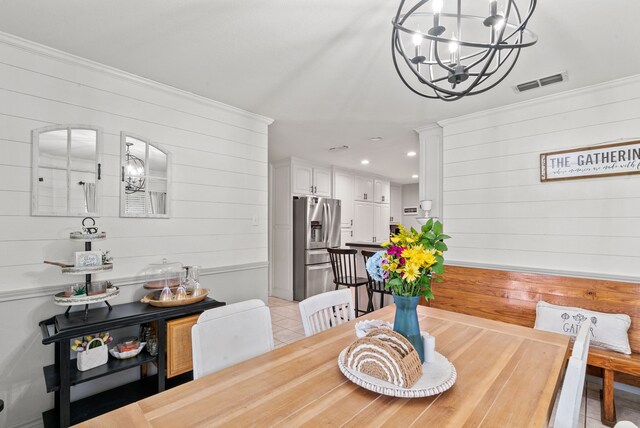 dining space featuring wood walls, light tile patterned floors, and a notable chandelier