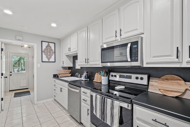 kitchen with appliances with stainless steel finishes, light tile patterned floors, sink, and white cabinets