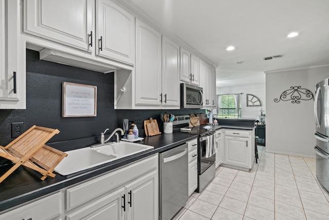 kitchen featuring appliances with stainless steel finishes, white cabinetry, light tile patterned floors, and sink